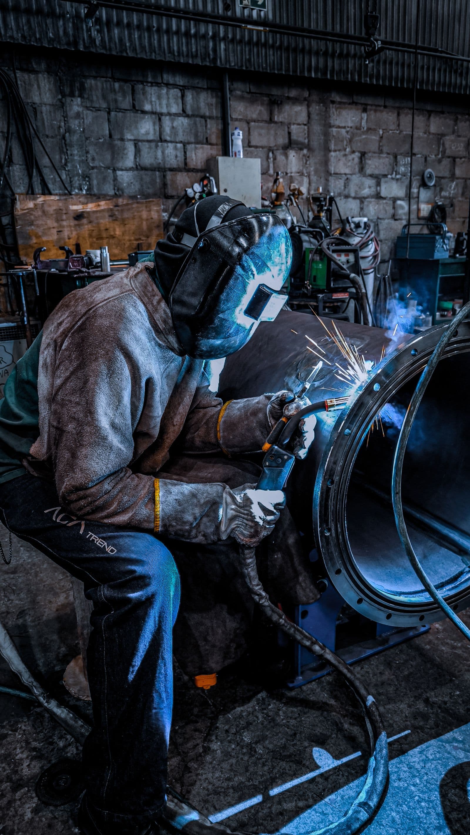 A welder joining a large steel flange in a fabrication shop